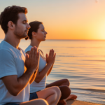 Two people seated beside calm water at sunrise with their hands held together.