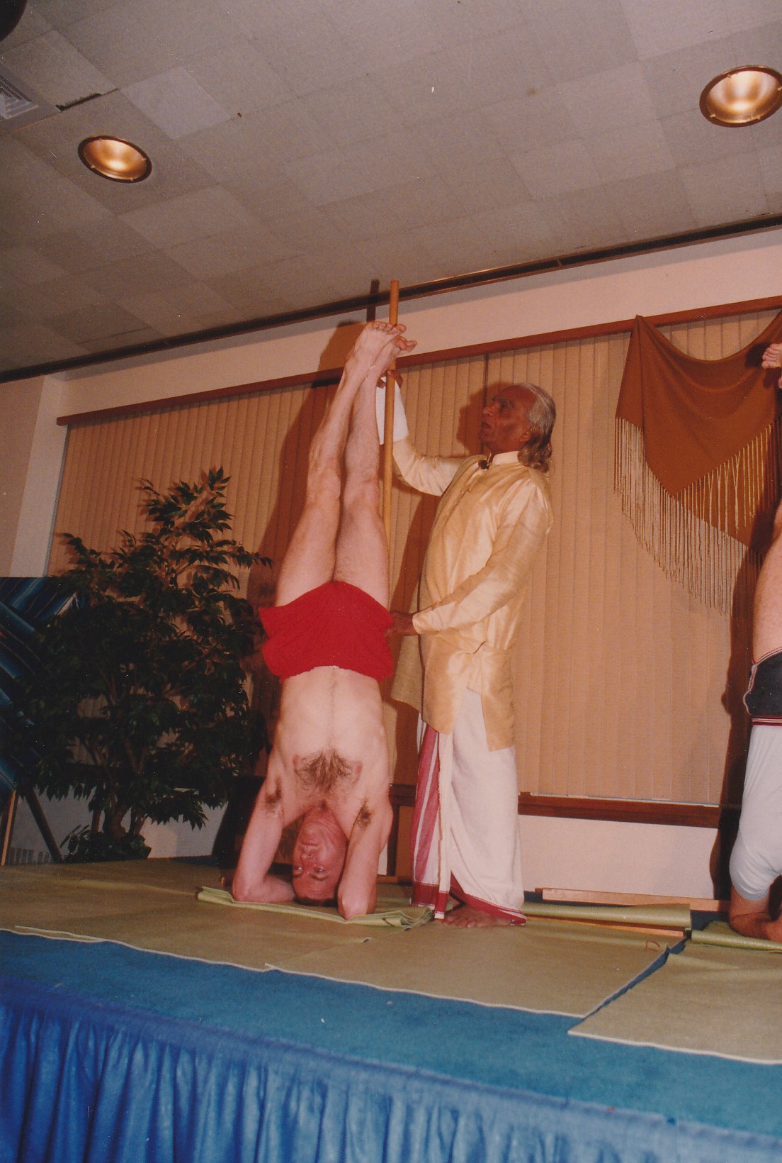 B. K. S. Iyengar guiding James Traverse in a headstand variation on the conference stage in Edmonton in 1990.